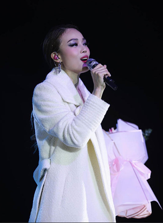Hong Kong singer and Cantopop diva Joey Yung is wearing the SENTALER Bouclé Alpaca Long Notched Collar Wrap Coat in Ivory White on stage performing.