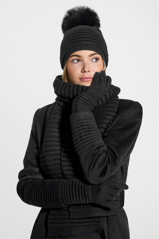 Sentaler Adult Ribbed Hat With Oversized Fur Pompon, Adult Ribbed Scarf and Adult Ribbed Gloves featured in Baby Alpaca and available in Black. Seen from front on model.