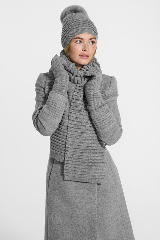 Sentaler Adult Ribbed Scarf, Ribbed Hat with Oversized Fur Pompon, Ribbed Gloves featured in Baby Alpaca and available in Grey. Seen from side on model.